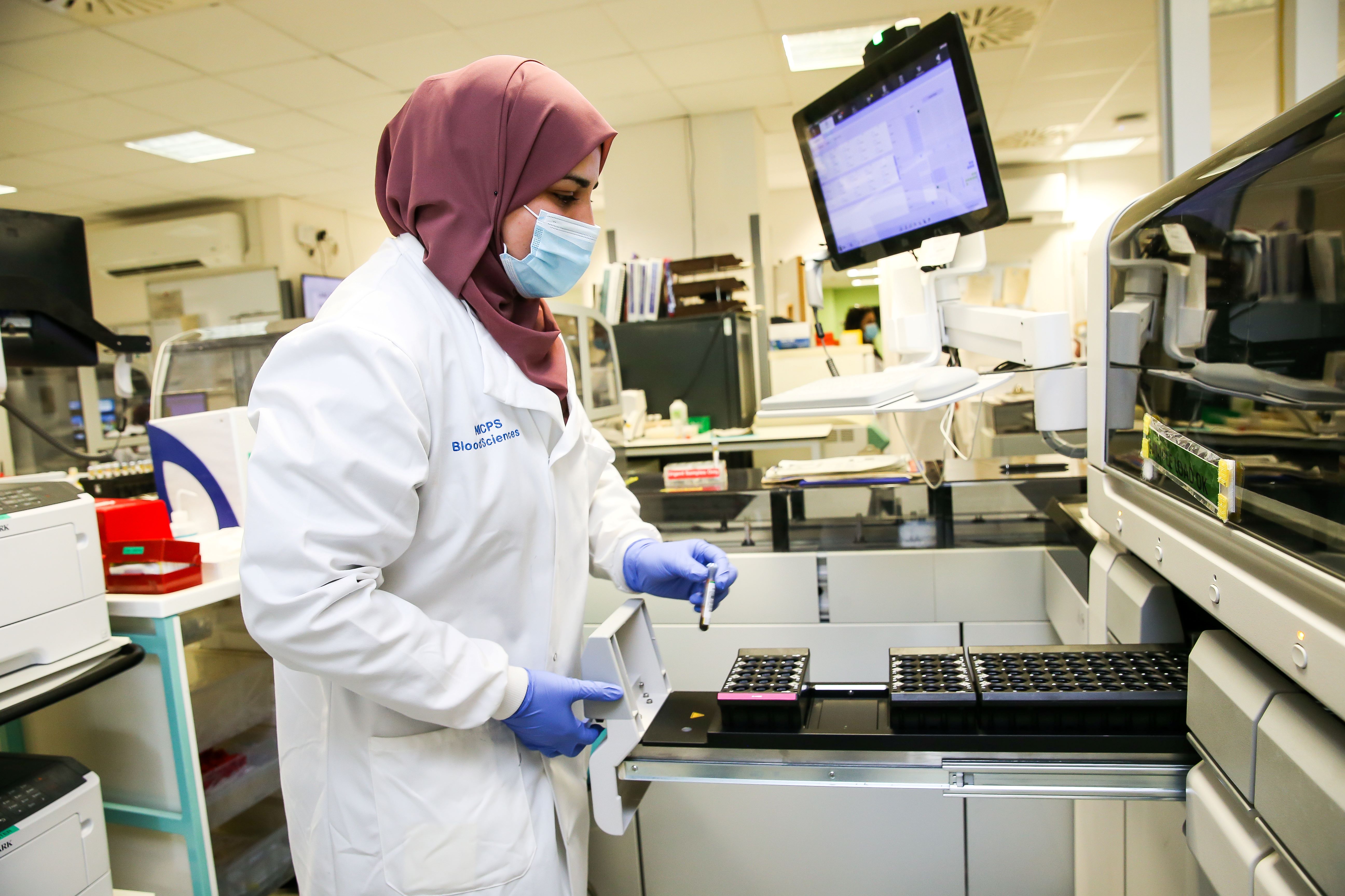 Pathology lab staff member putting test together in front of computer